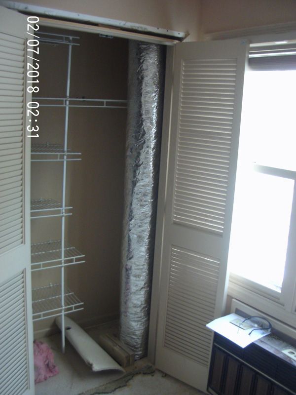 Open closet with wire shelving and sliding doors, one door open beside a bright window.