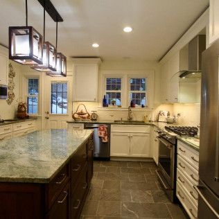 Bright modern kitchen with granite island, pendant lights, white cabinets, and gas stove