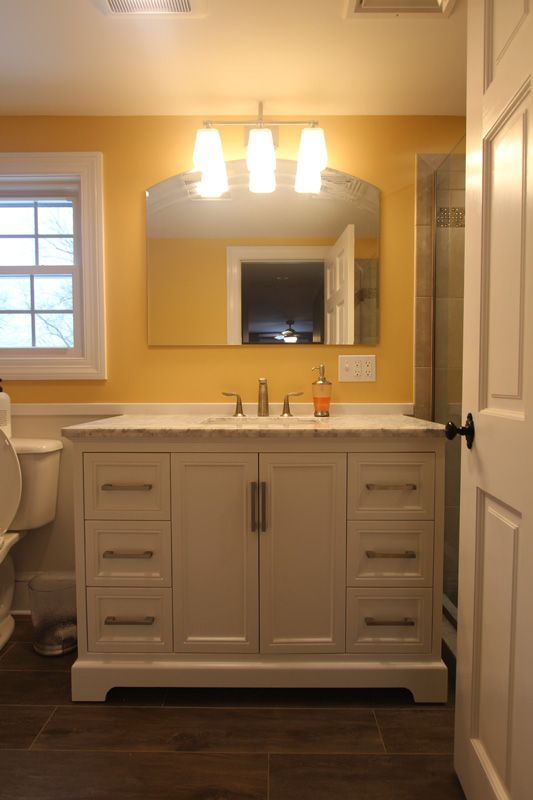 Bathroom vanity with mirror, lights, and white cabinet against yellow walls