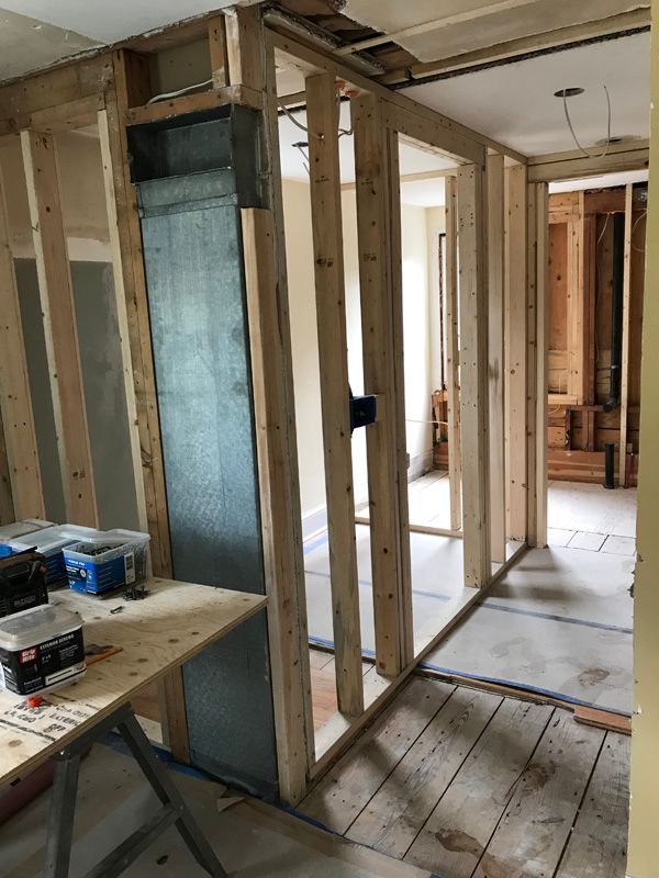 Unfinished interior wall framing in a house under construction, with exposed studs, wiring, and a wooden floor.