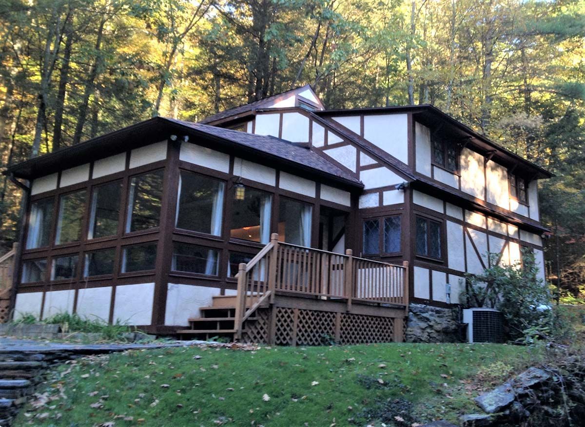Rustic cabin with screened porch in a wooded forest clearing