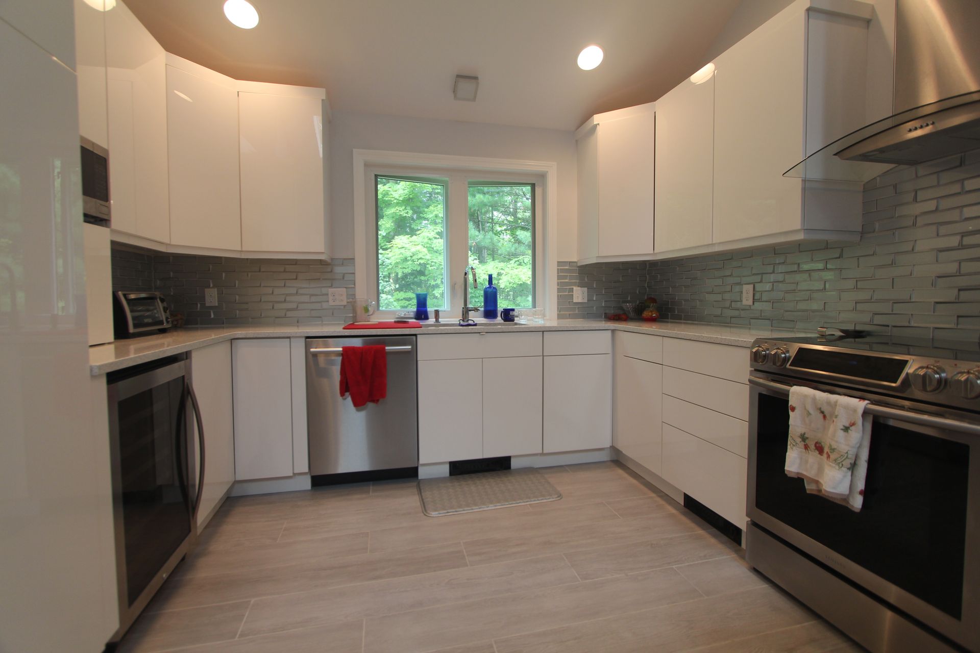 Bright modern kitchen with white cabinets, stainless appliances, and a window over the sink
