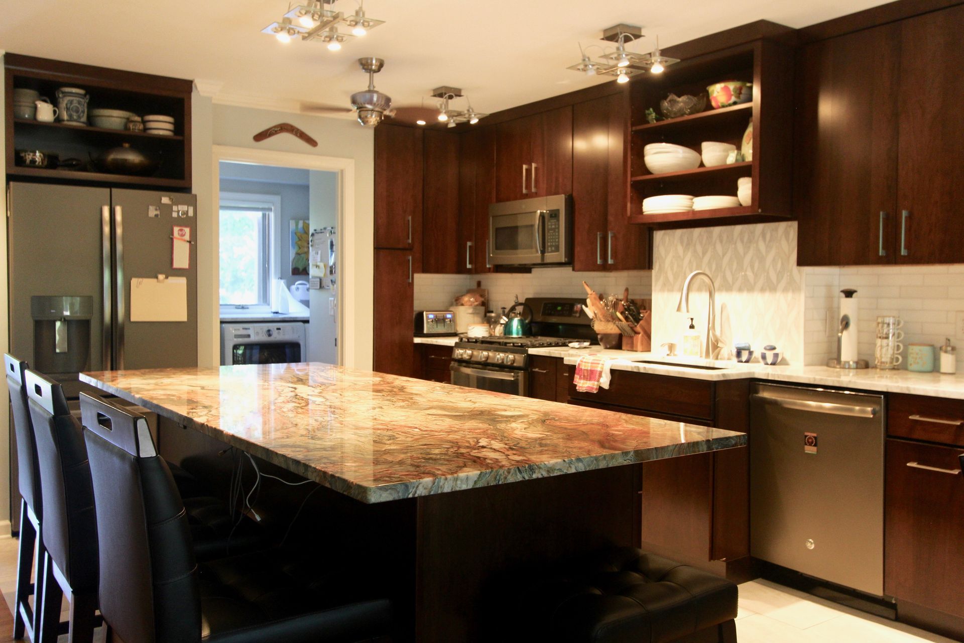 Modern kitchen with dark wood cabinets, granite island, and stainless steel appliances