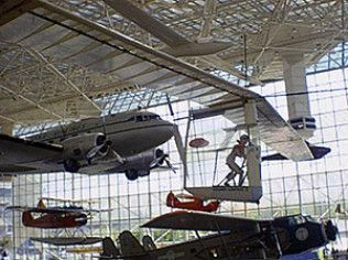 Airplane hangar with a suspended silver plane and a person on a maintenance platform