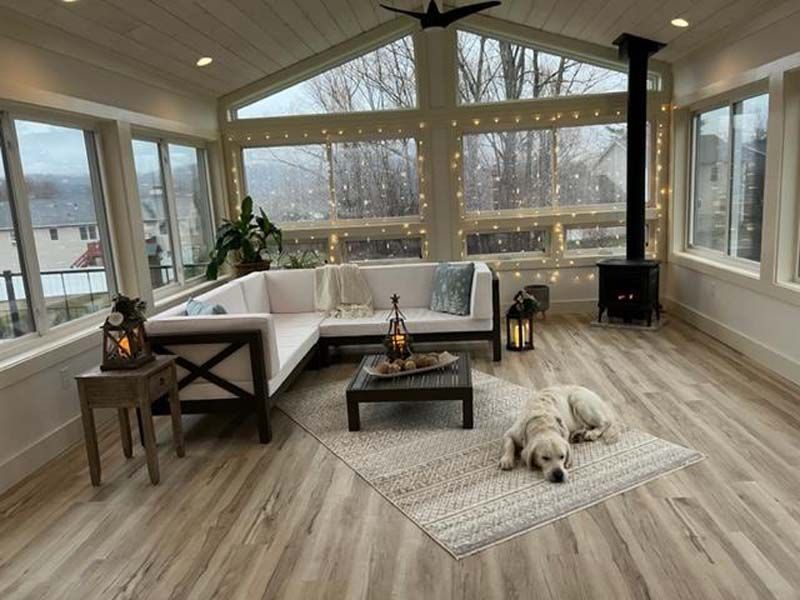 Cozy sunroom with white sectional, wood table, lanterns, and a sleeping dog on a rug.