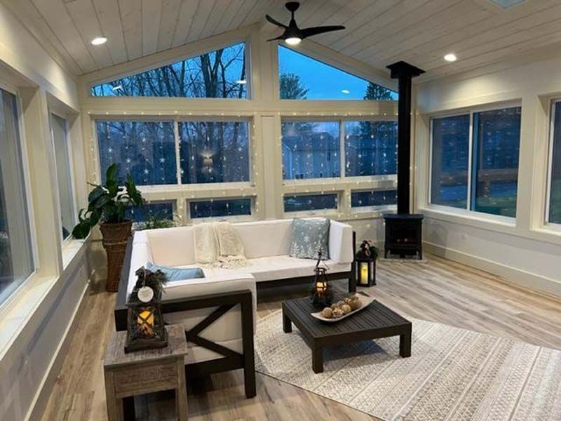 Modern living room with a white sofa, large windows, vaulted ceiling, and lake view at dusk