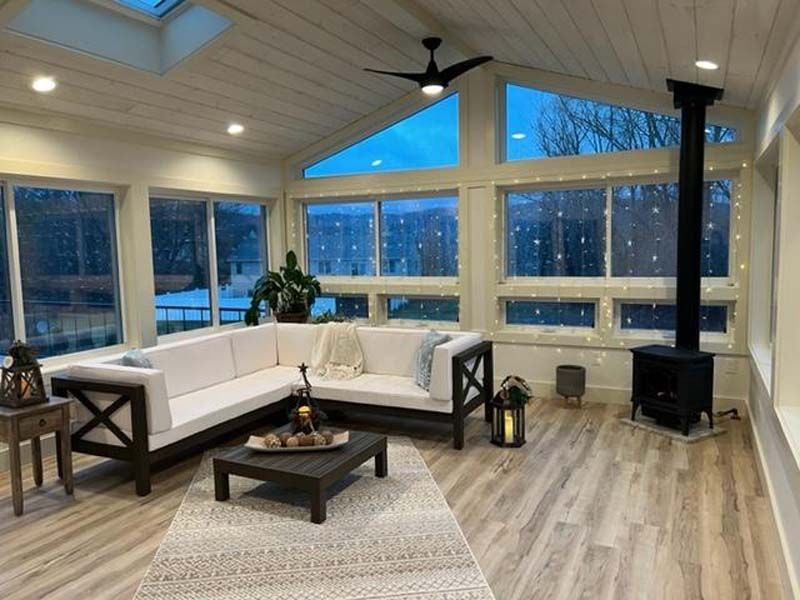 Modern living room with white sectional sofa, wood coffee table, and large windows at dusk