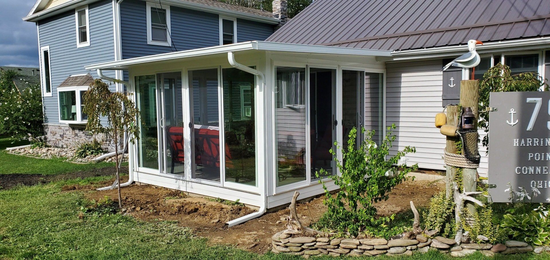 A blue house with a white sunroom attached to it.