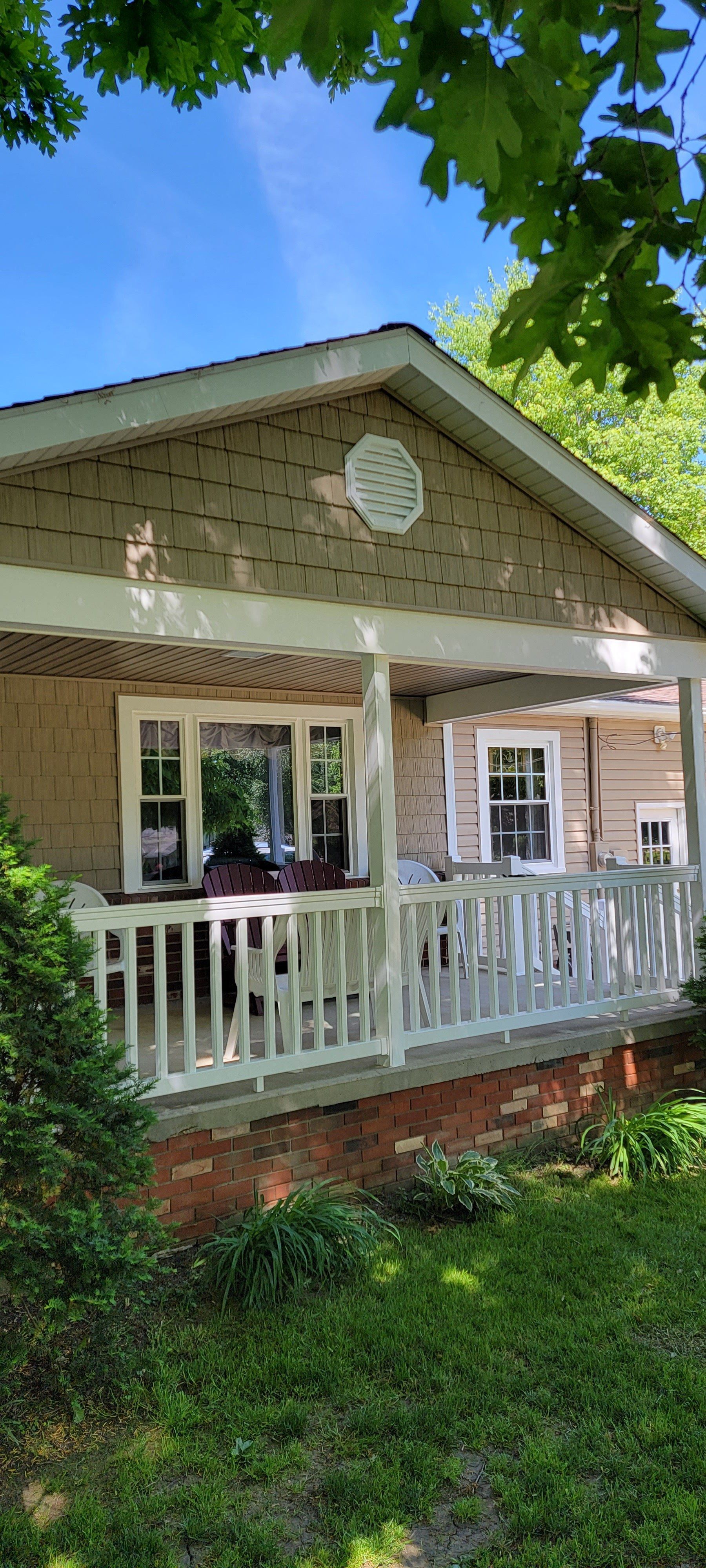 A house with a porch and a white railing on a sunny day.
