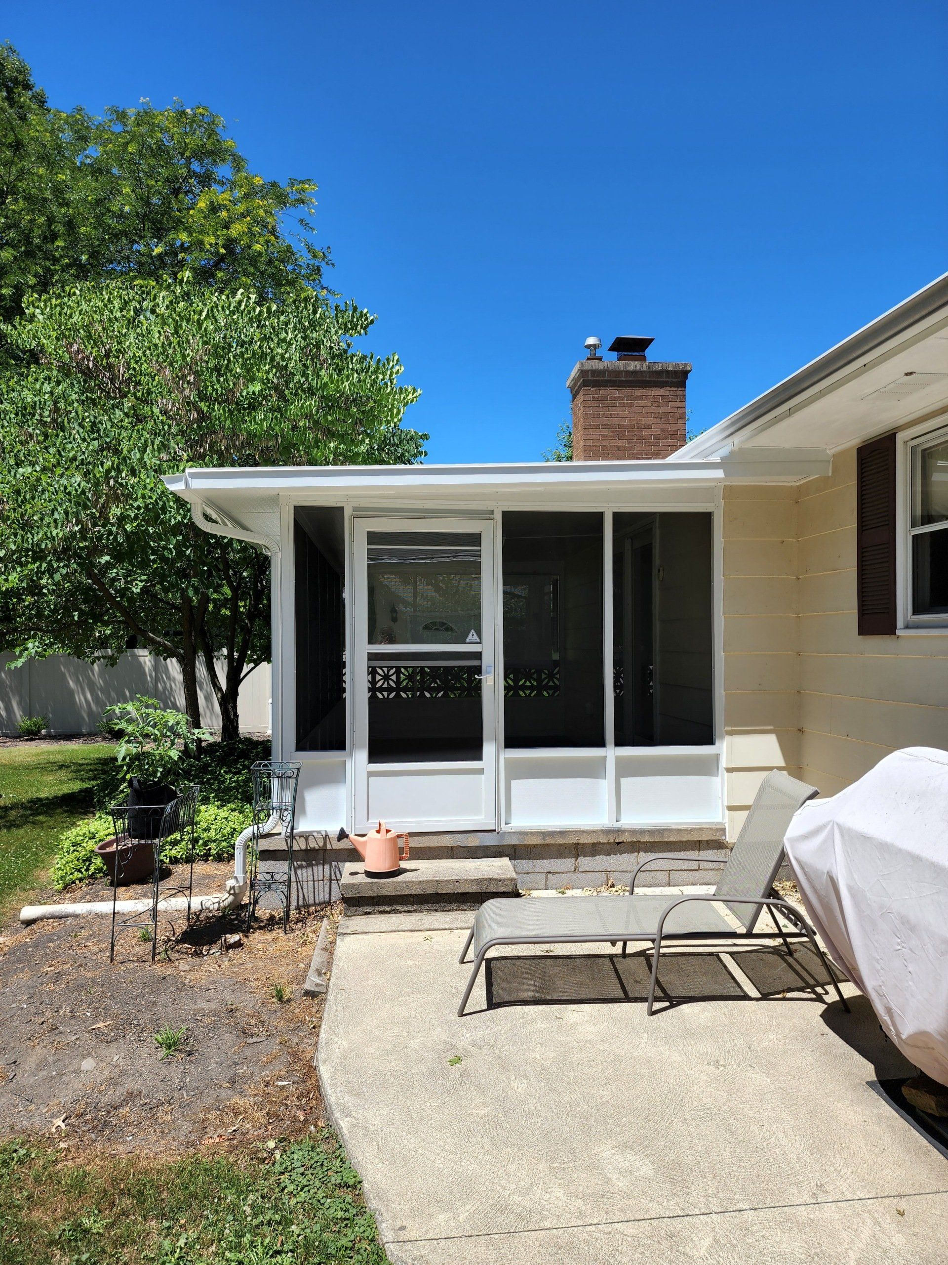 There is a screened in porch in the backyard of a house.
