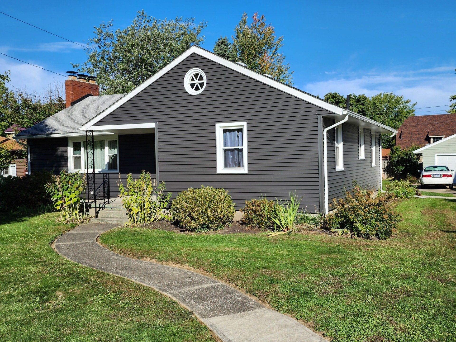 A small house with a walkway leading to it and a car parked in front of it.