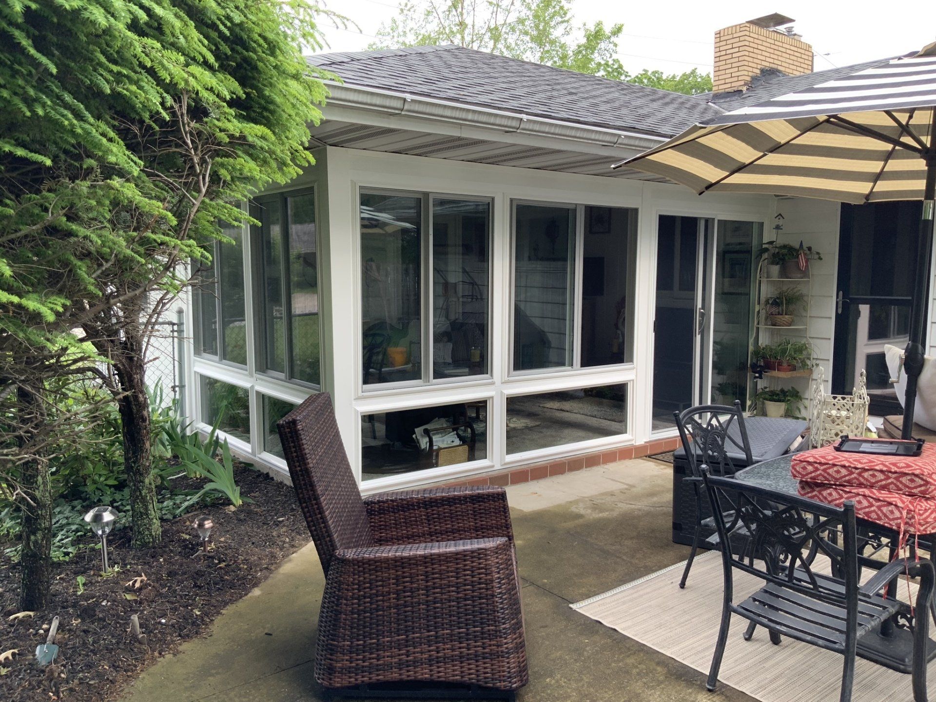 A patio with a table and chairs and an umbrella in front of a house.