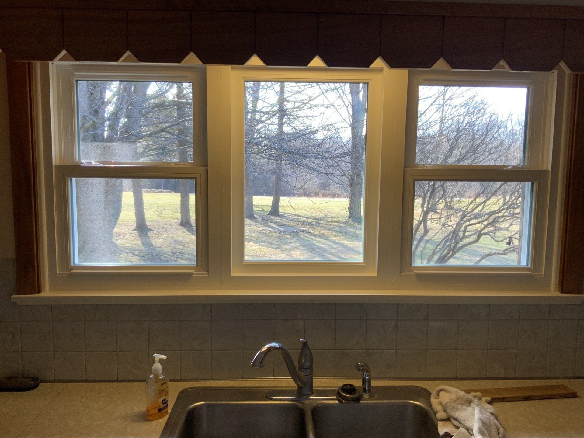 A kitchen with a sink and a window with a view of trees