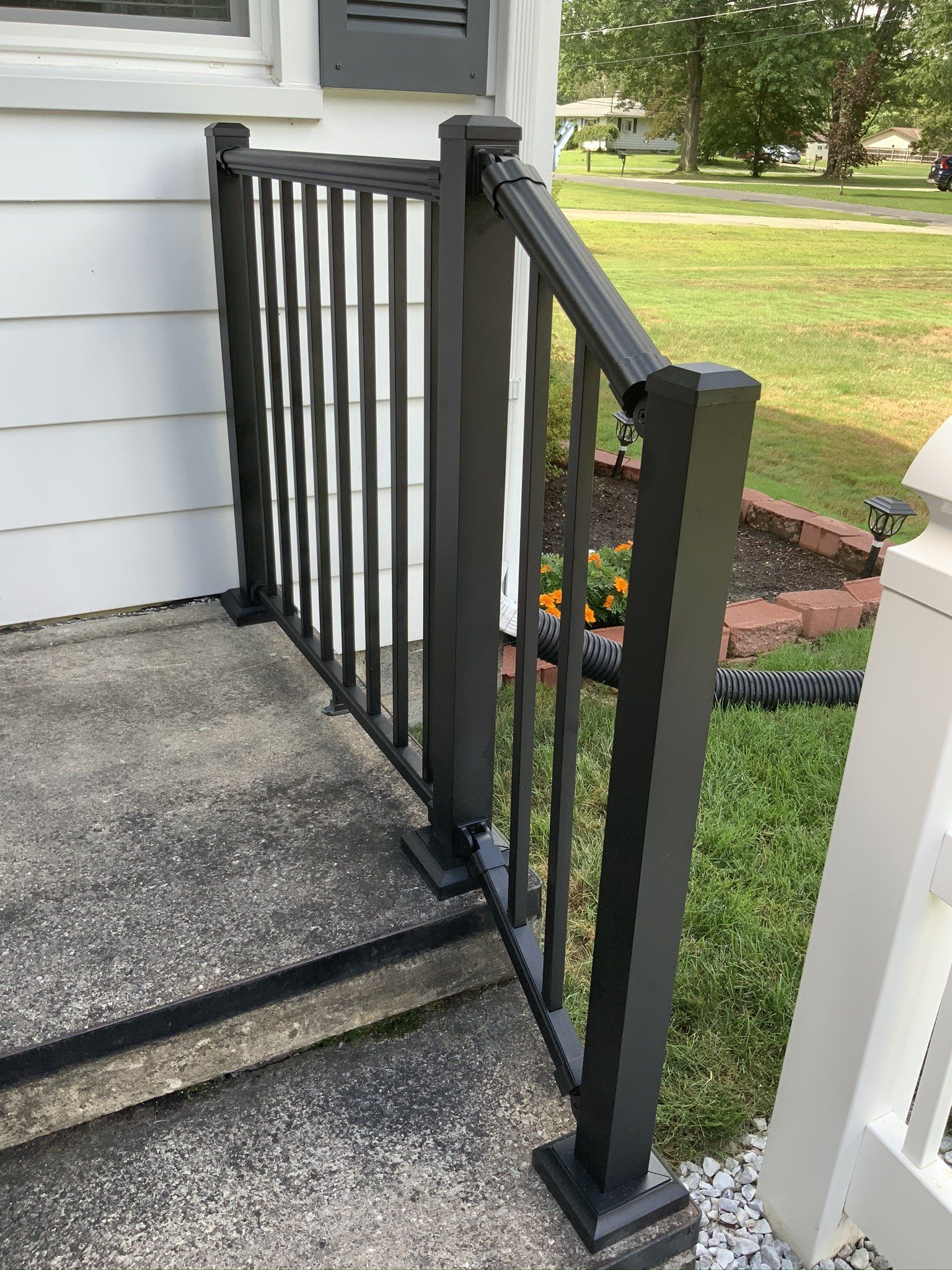 A black railing on a porch next to a white house.
