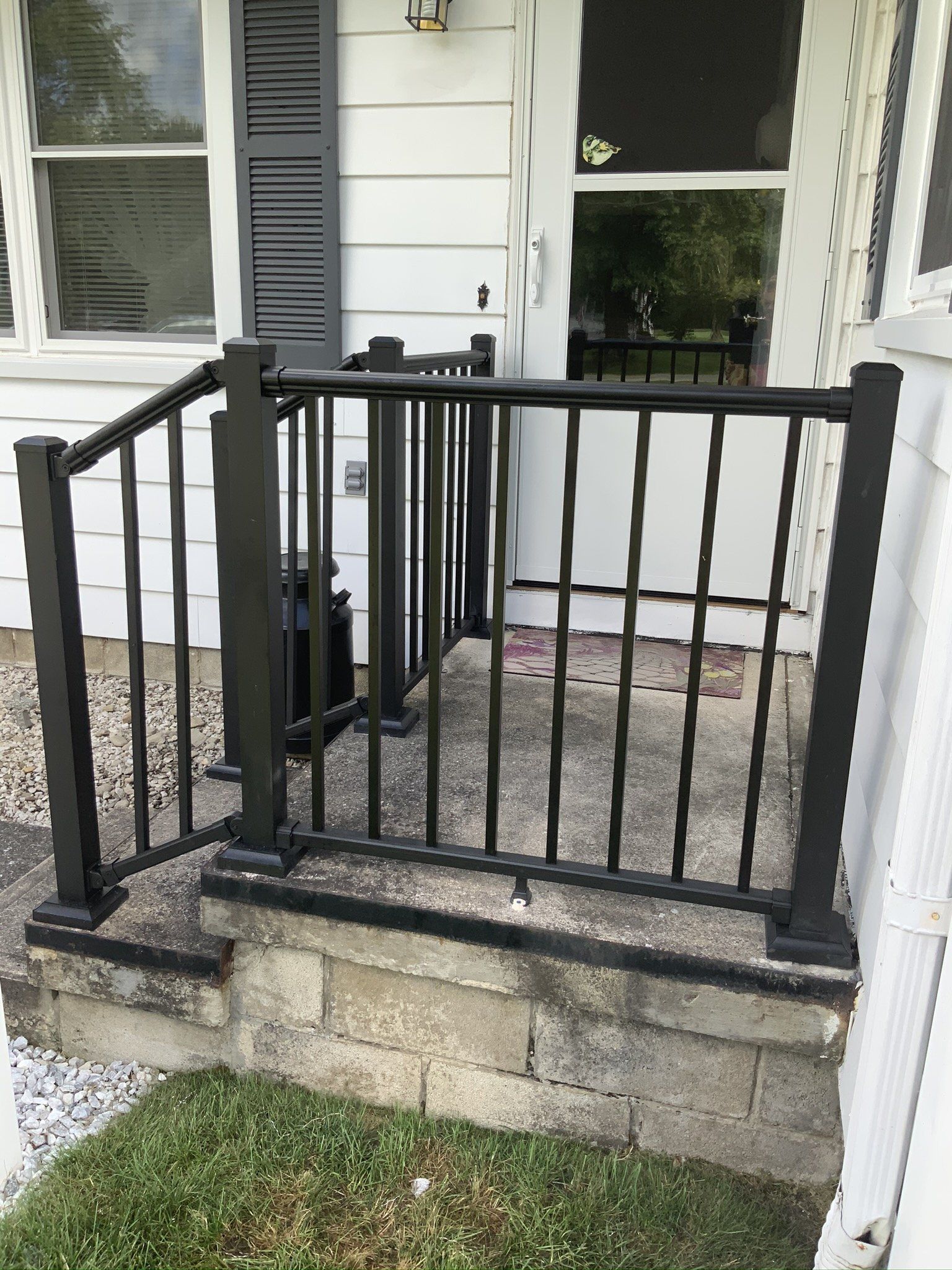 A white house with a black railing on the porch.