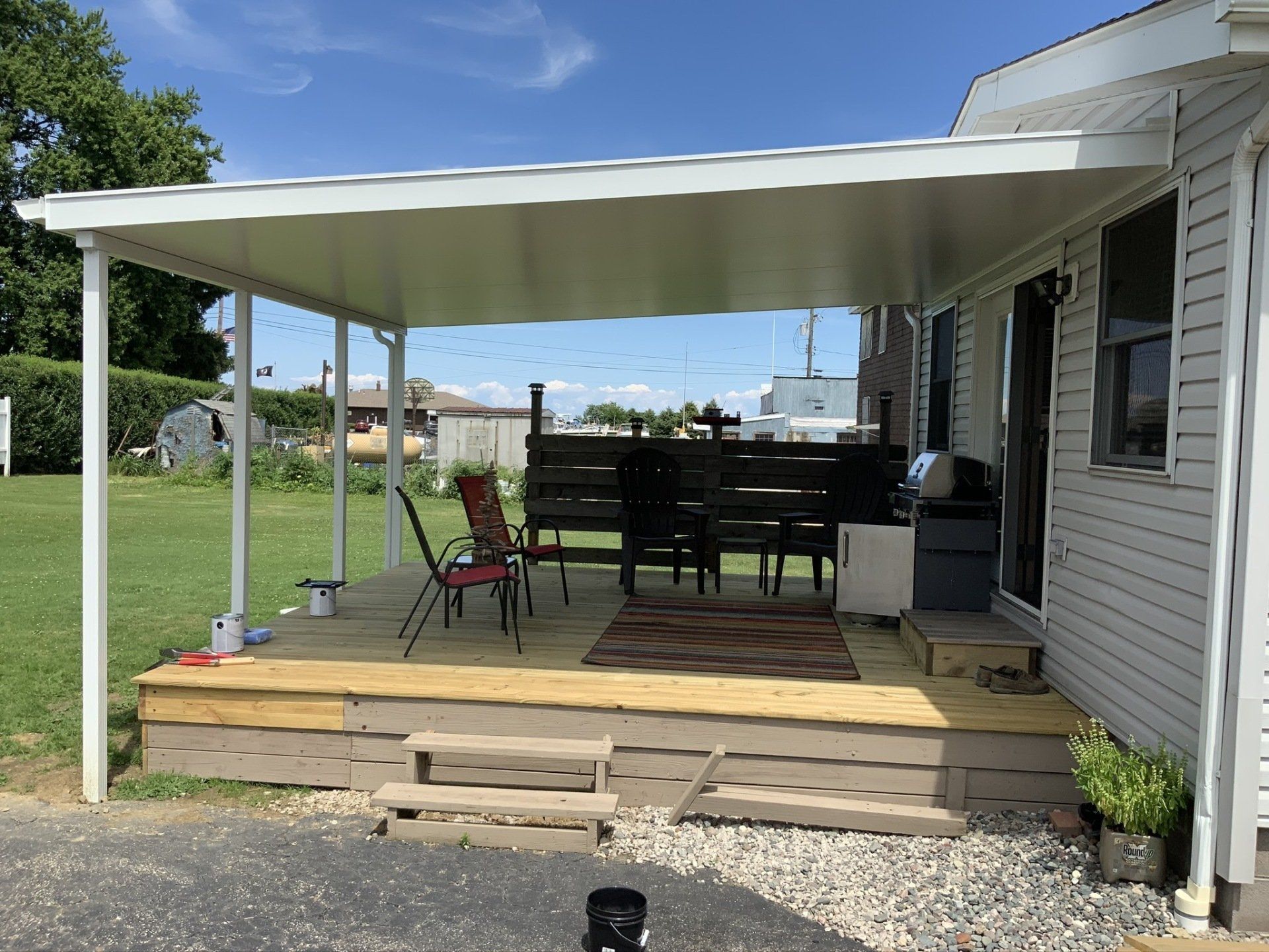 A mobile home with a covered porch and a wooden deck.
