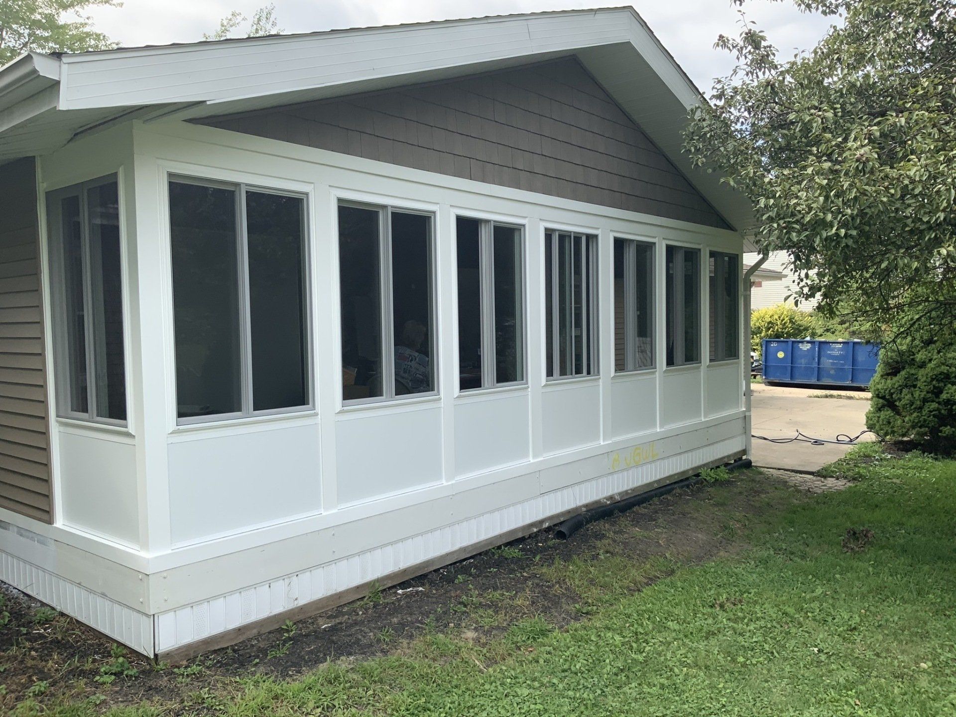 A house with a screened in porch and lots of windows.