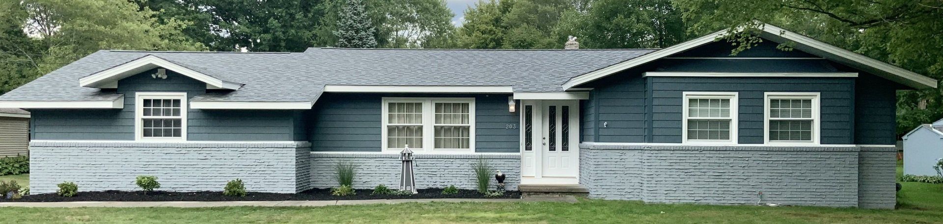 A blue house with white windows and a gray roof