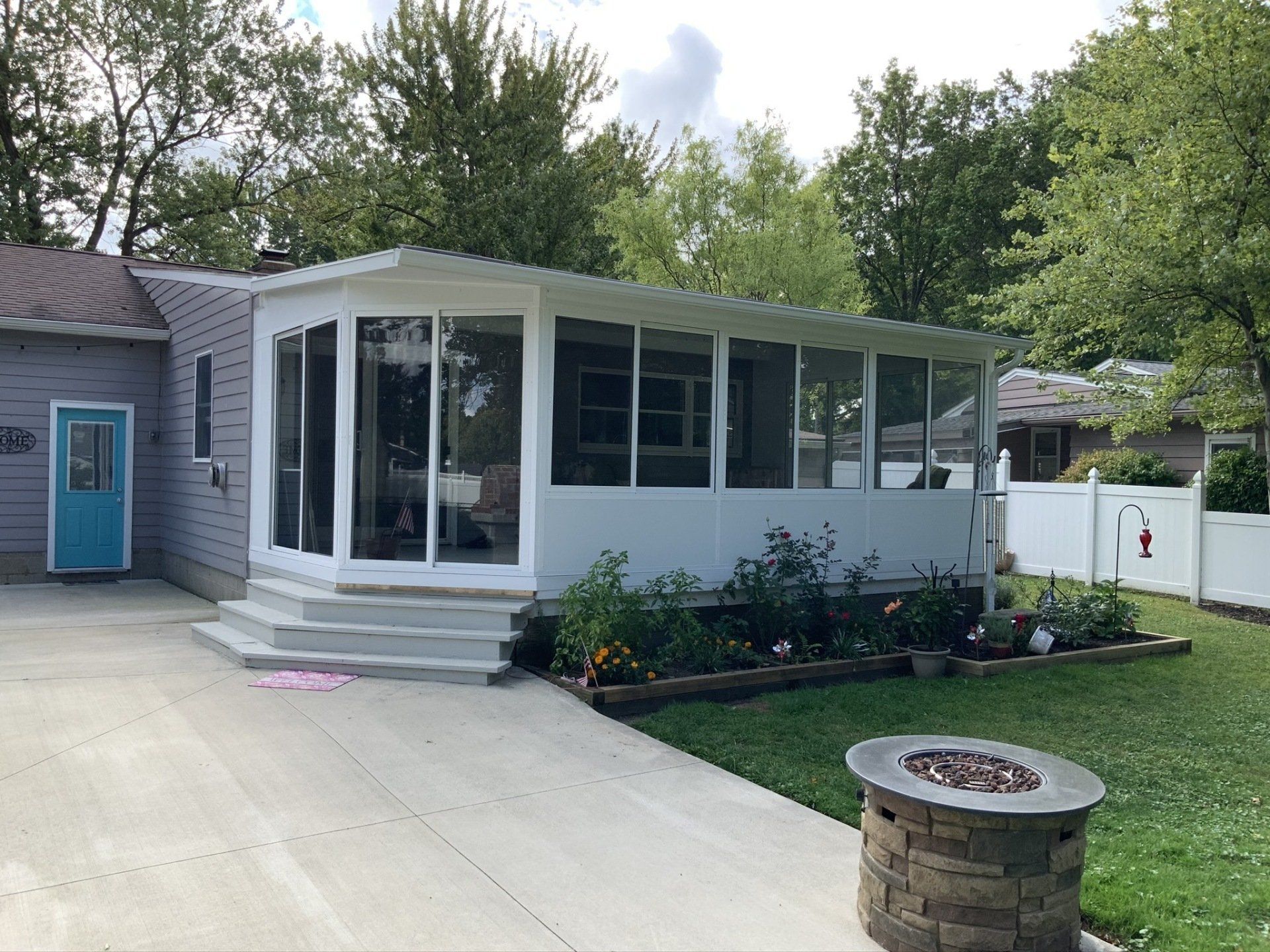 A house with a screened in porch and a fire pit in front of it.