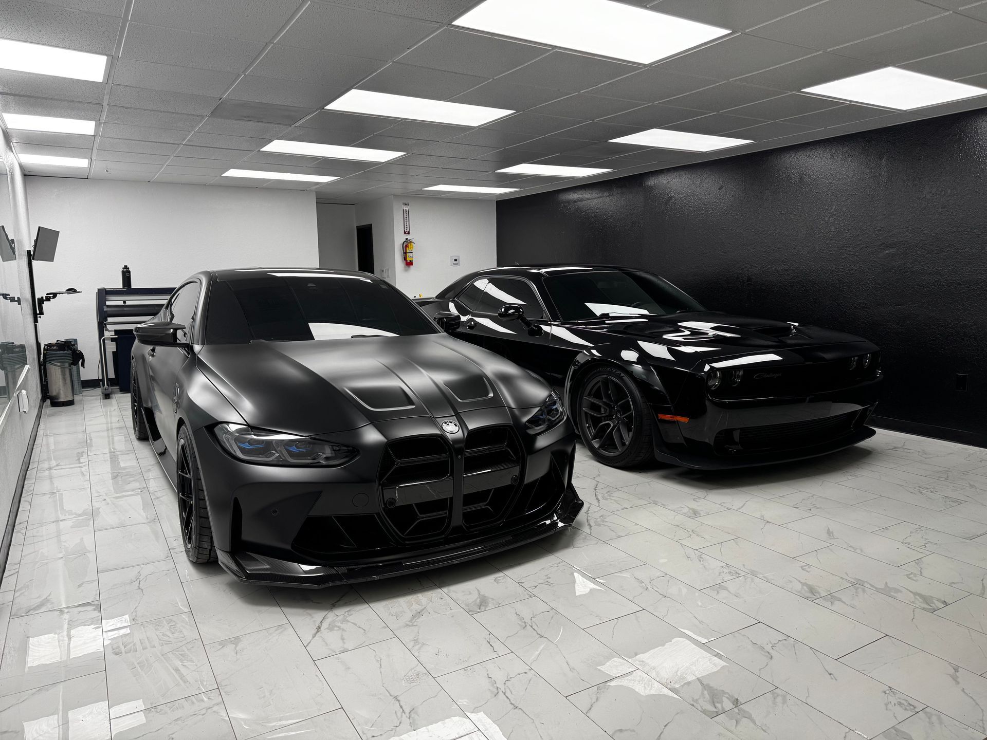 Two black sports cars parked in a bright indoor showroom with tiled floor