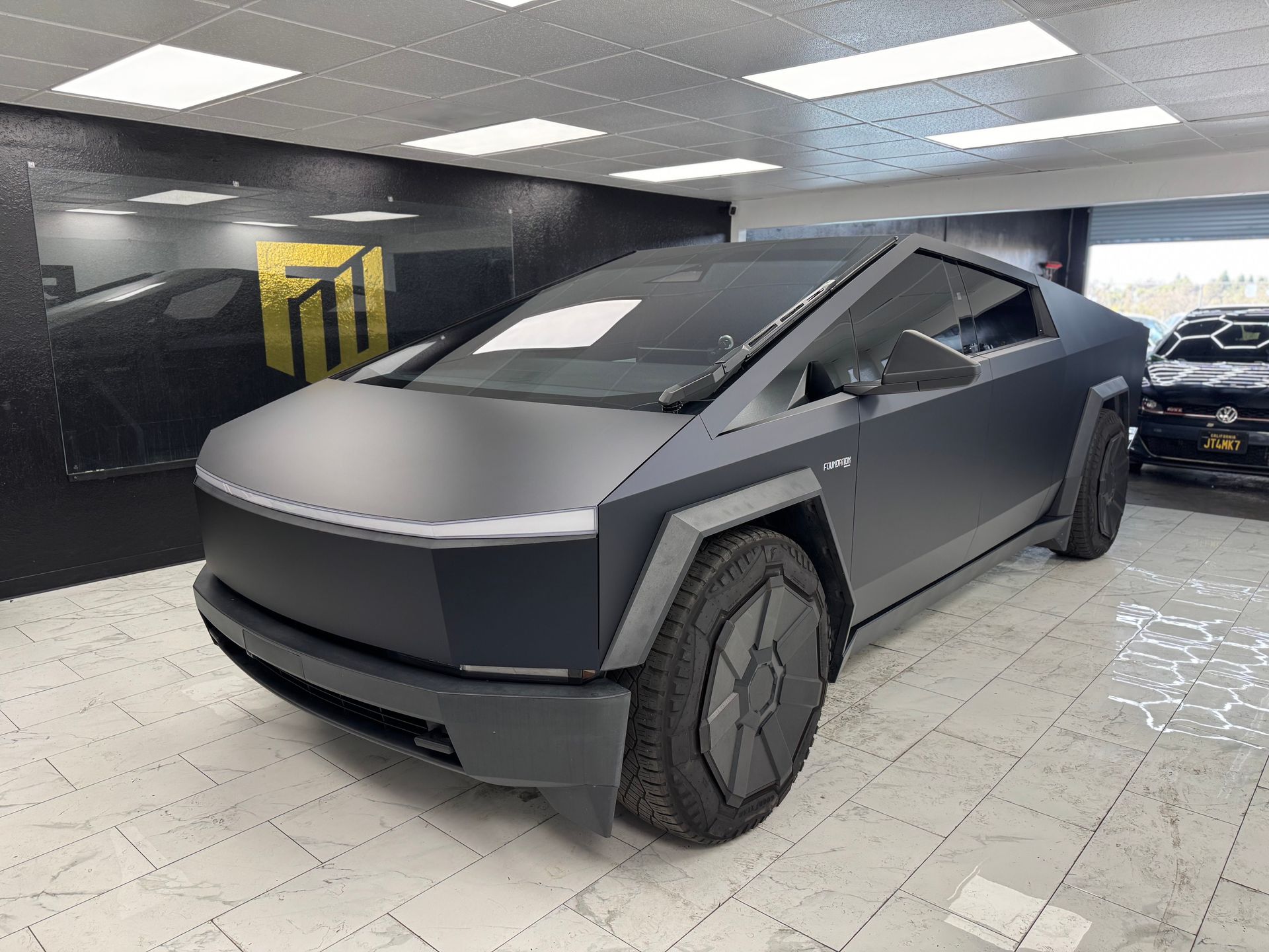Matte black Tesla Cybertruck in a showroom, viewed from the front-left side.