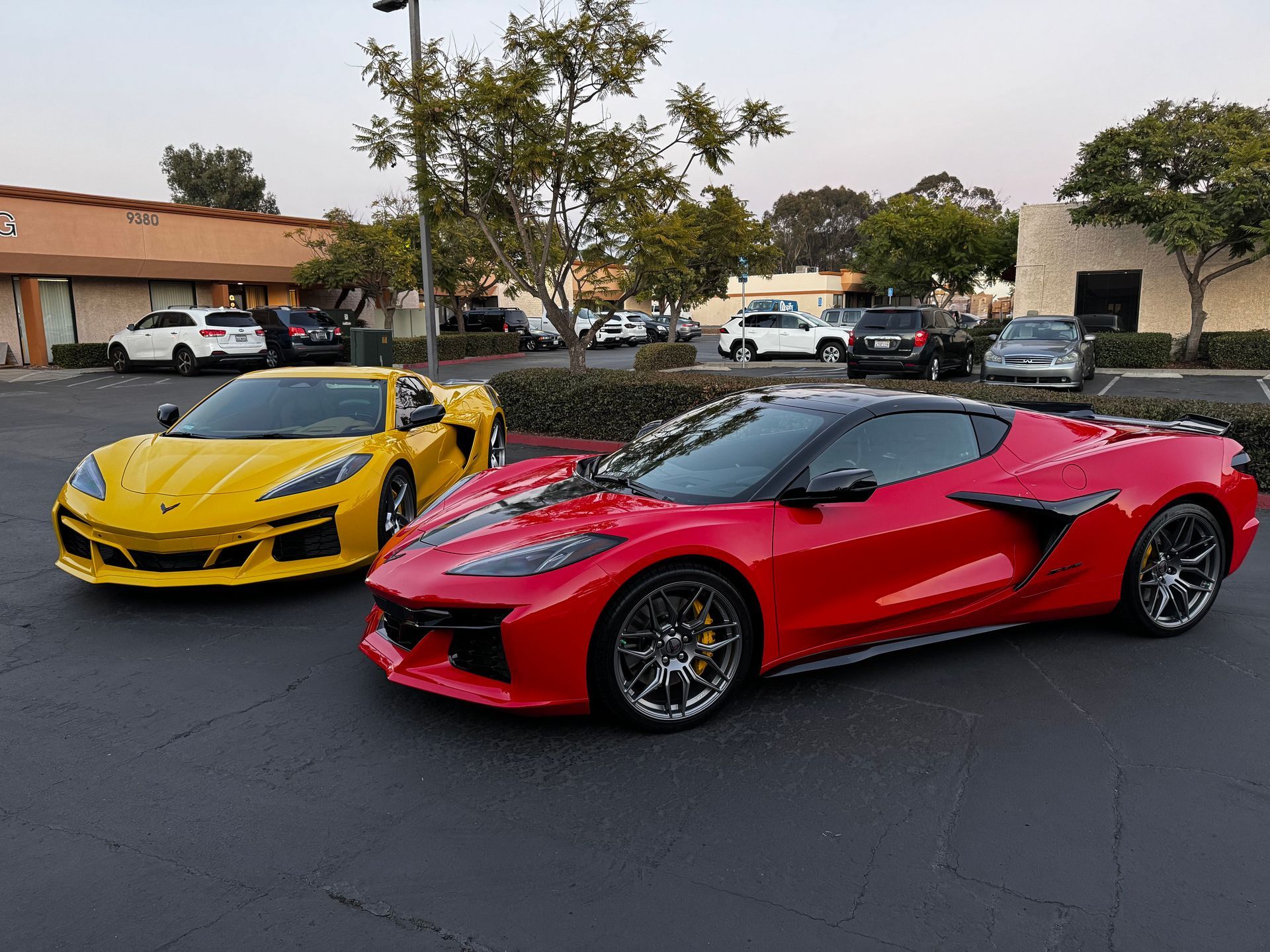 Red and yellow sports cars parked in a lot outside a shopping center.