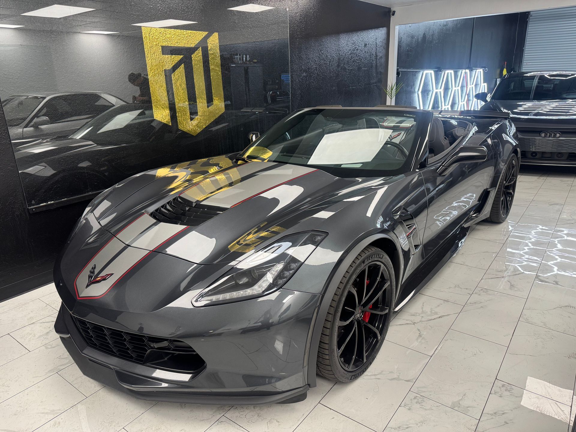 Detailing a red sports car hood and headlight with a microfiber cloth in a garage