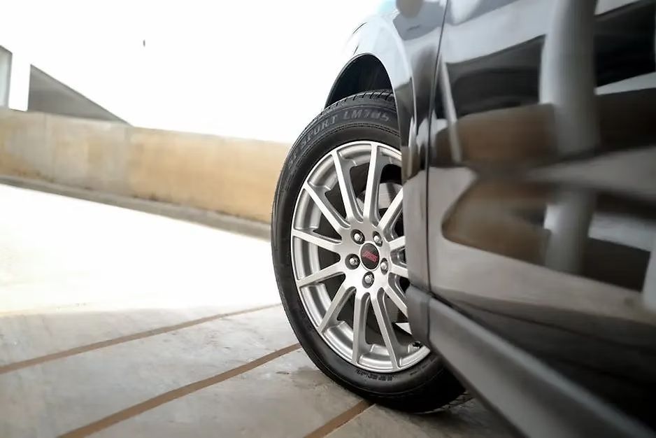 Silver car wheel parked by a concrete barrier in a garage