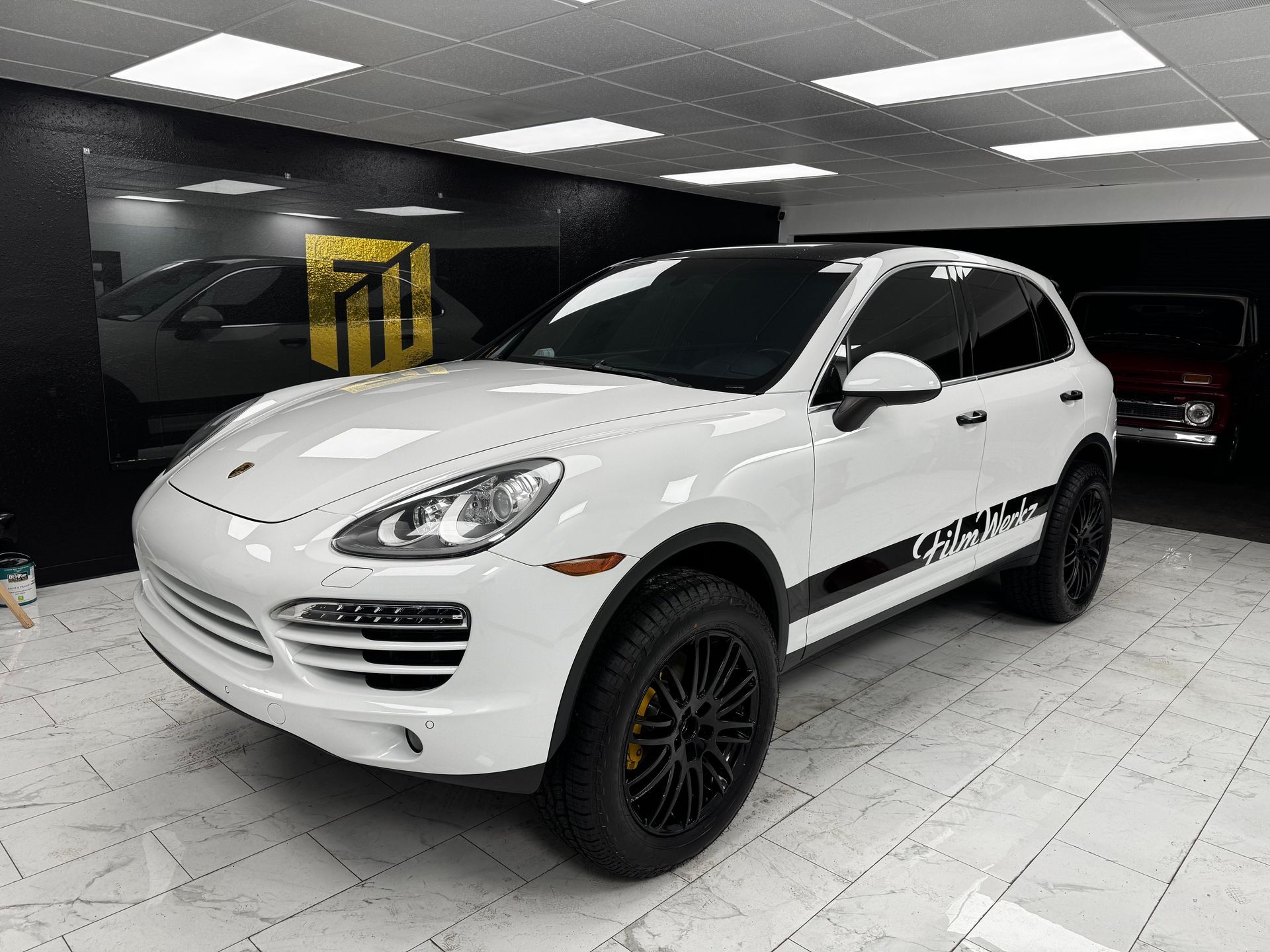 White Porsche SUV in a showroom with black wheels and a black side stripe
