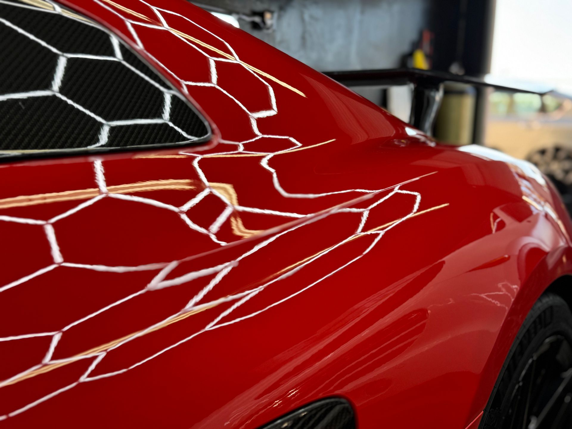 Close-up of a red sports car with a white geometric decal on the rear window and bodywork