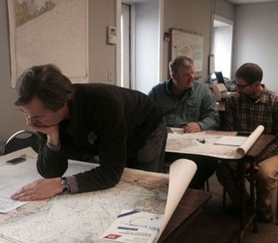 Three men are sitting around a table looking at a map