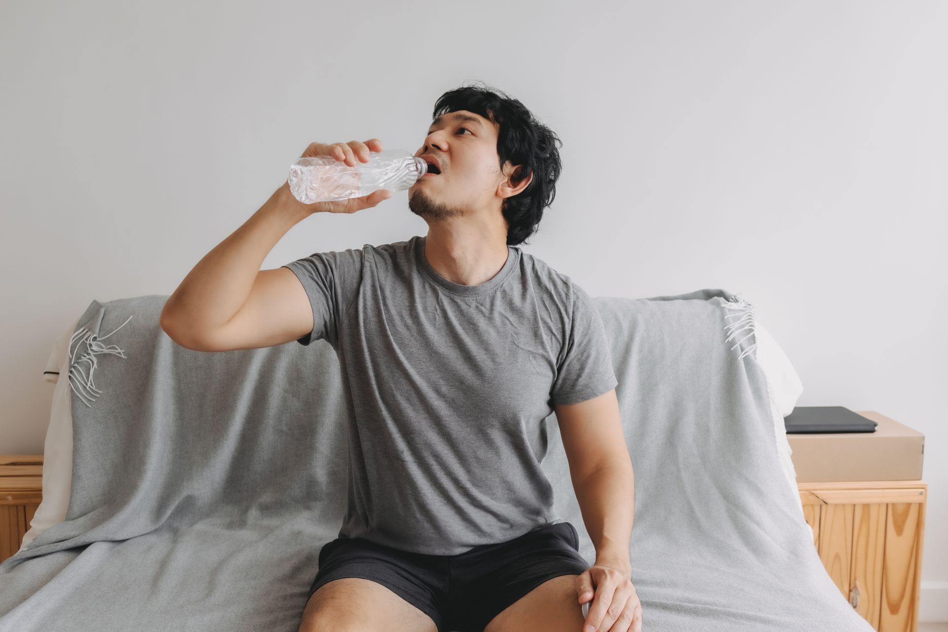 A man with norovirus drinks plenty of water to avoid dehydration.