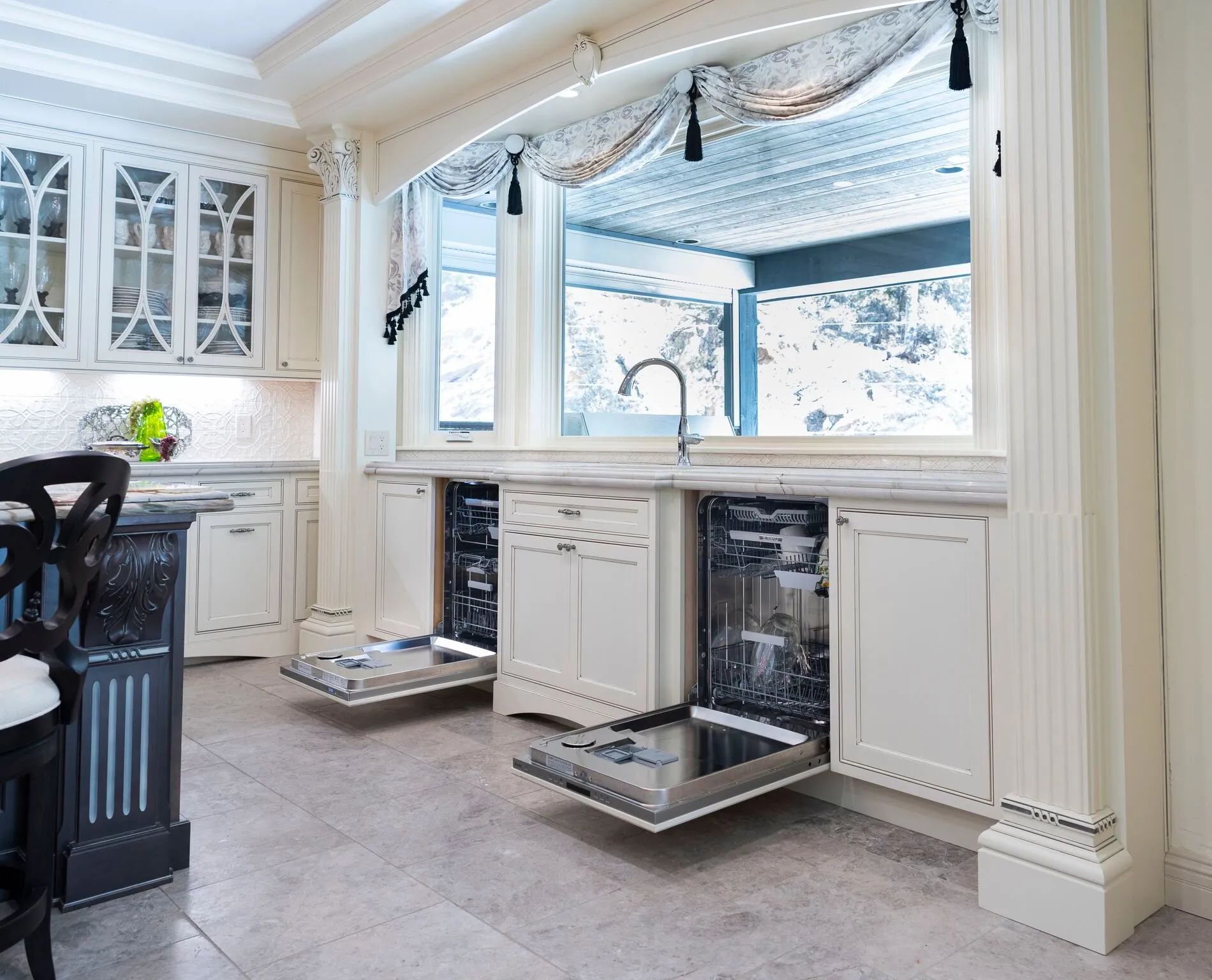 Kitchen with open dishwashers, overlooking a scenic outdoor view through a large window.