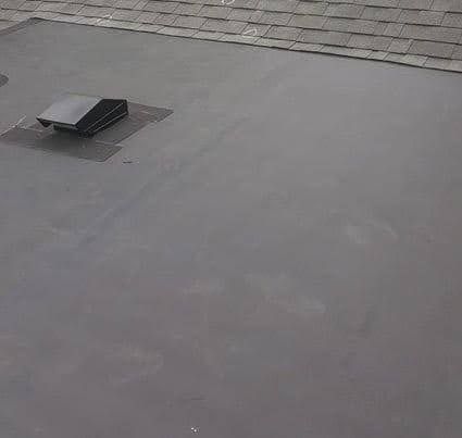 A close up of an EPDM membrane roof with a vent on it.