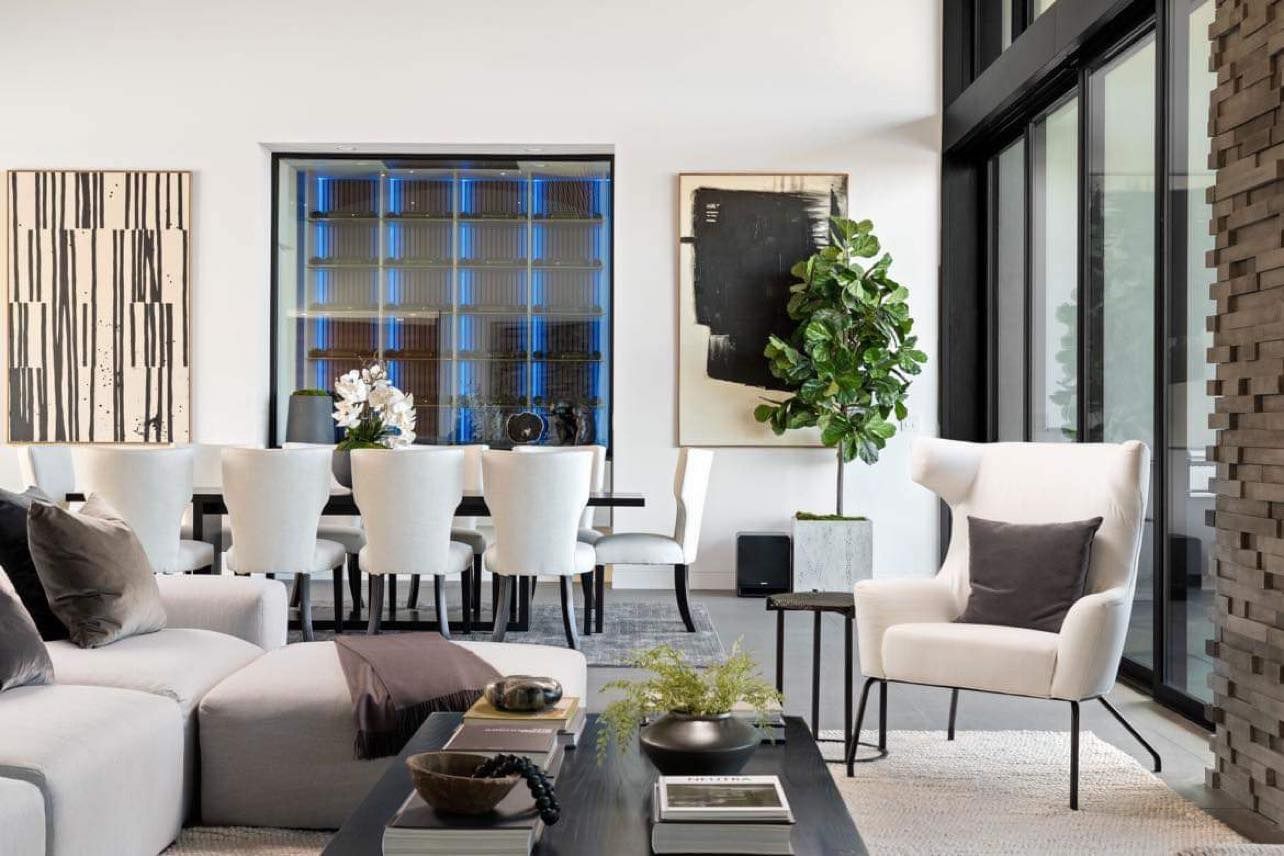 Modern living room with white furniture, black accents, and artwork.