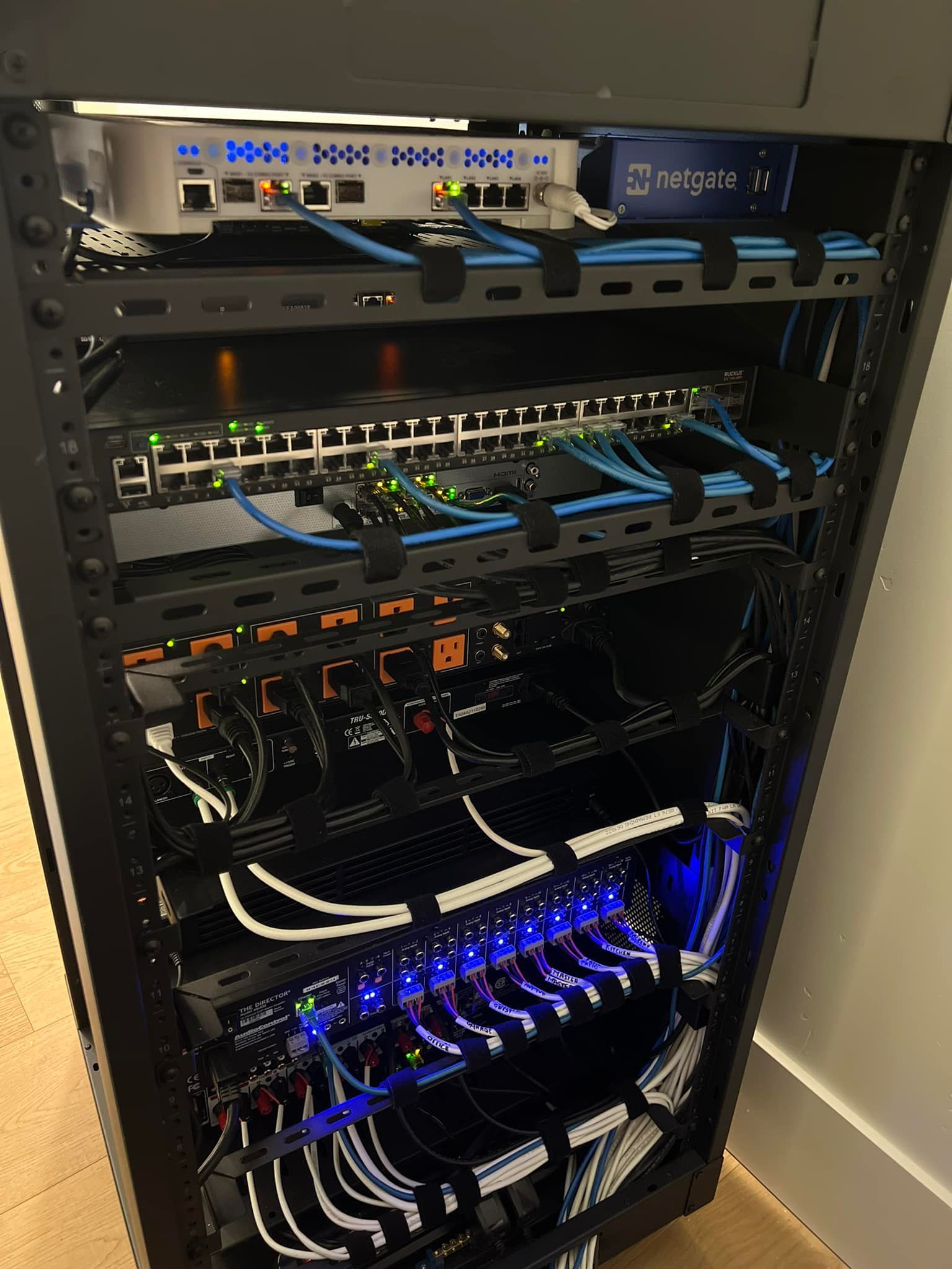 Network server rack with multiple devices, including switches, router, and patch panels, connected by cables.