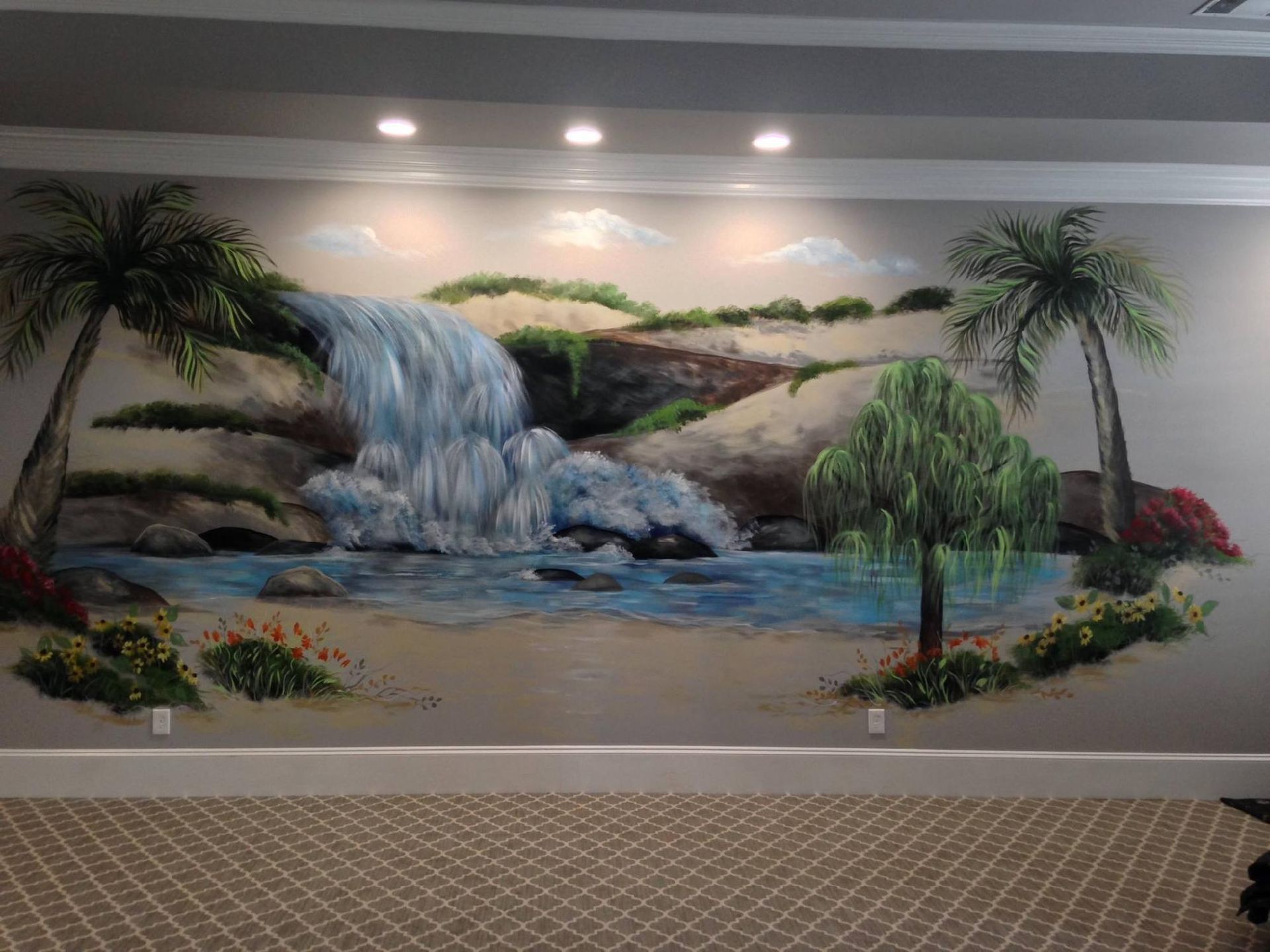 Mural of a waterfall with palm trees and foliage painted on a beige wall.