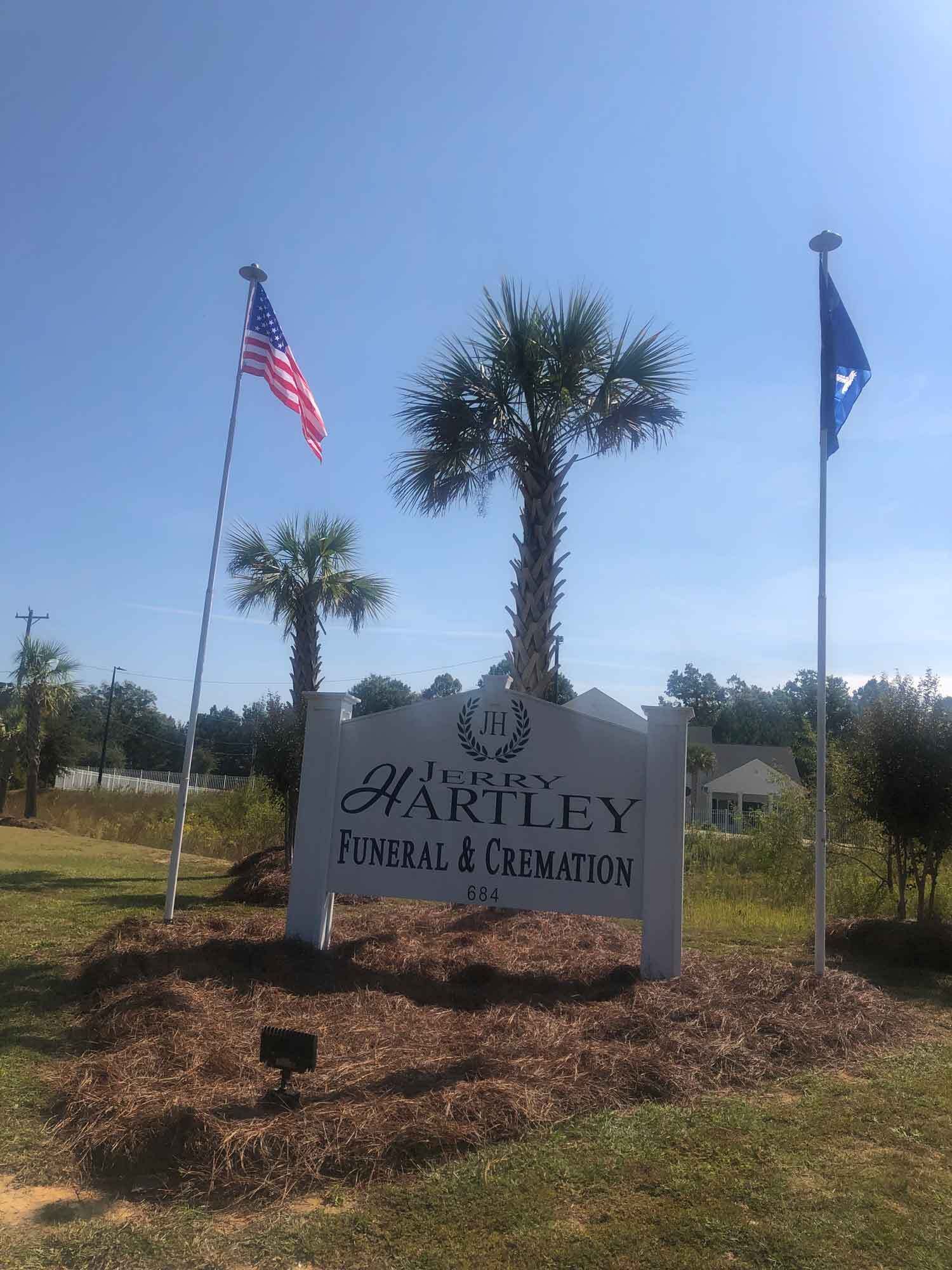 Sign for Horton-Hartley Funeral & Cremation with American flag and blue flag.