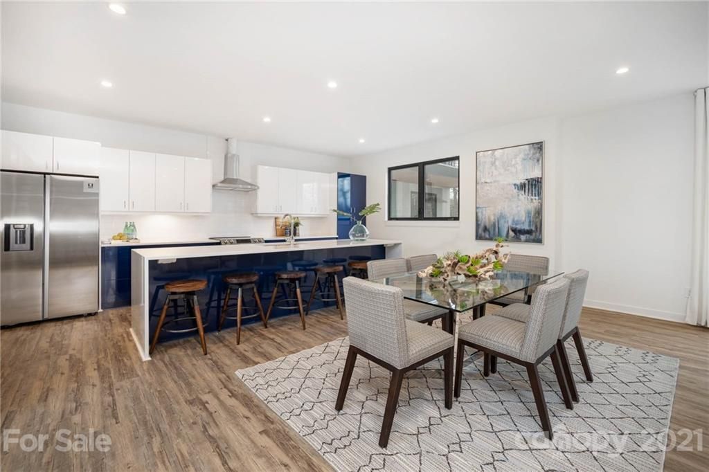 Modern kitchen/dining area with navy island, stainless steel appliances, and a table set for six.