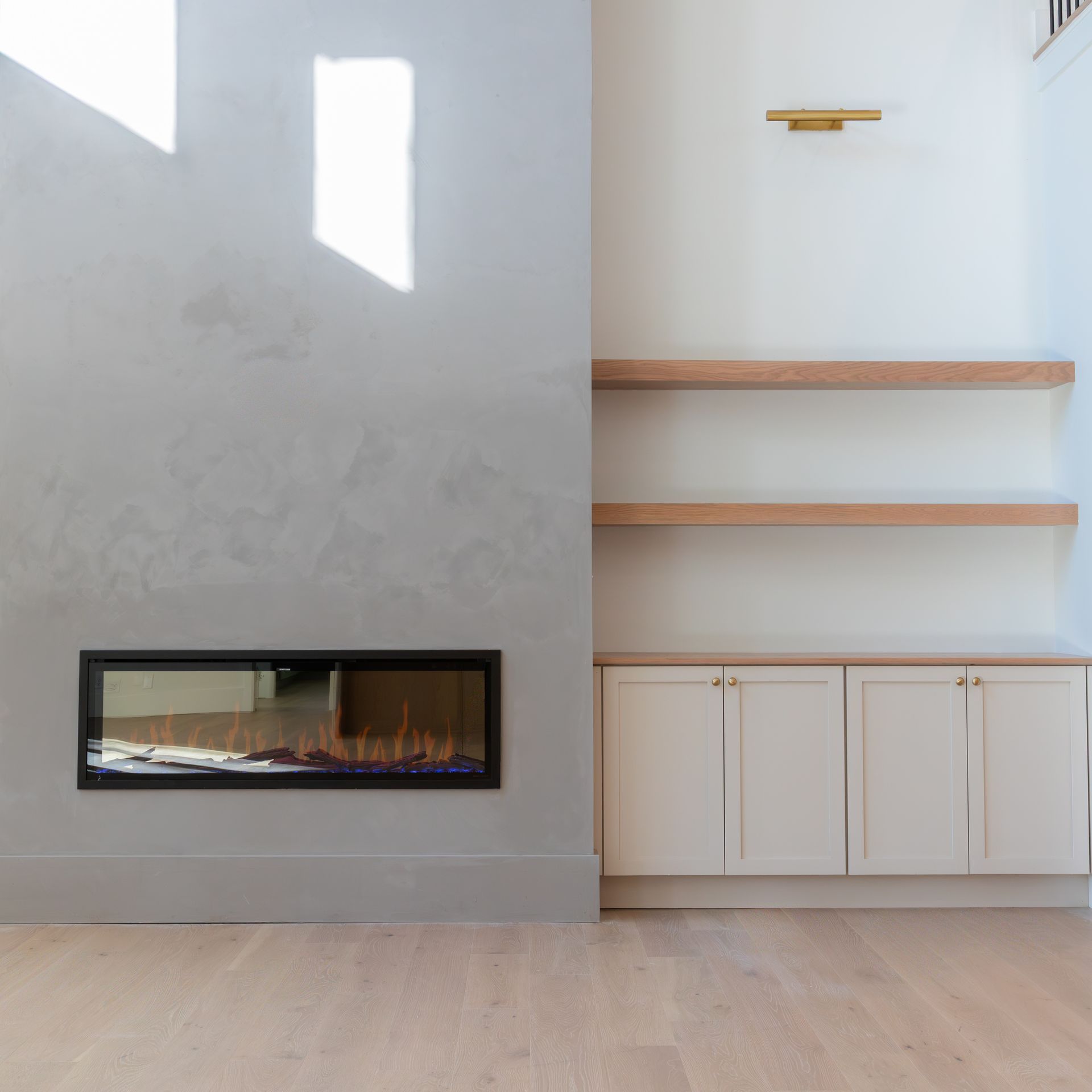 Modern living room: fireplace, built-in shelves, off-white cabinetry, light wood floors, and textured wall.