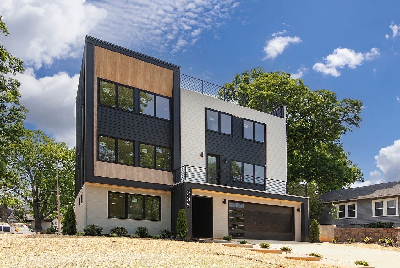 Modern multi-story home with wood, black, and white facade; sunny day.