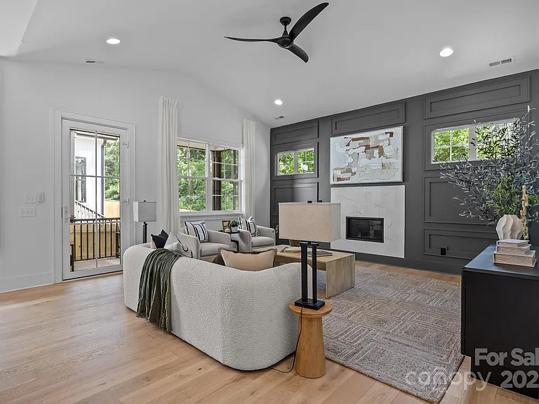 Living room with gray accent wall, fireplace, light sofa, rug, and door to balcony.