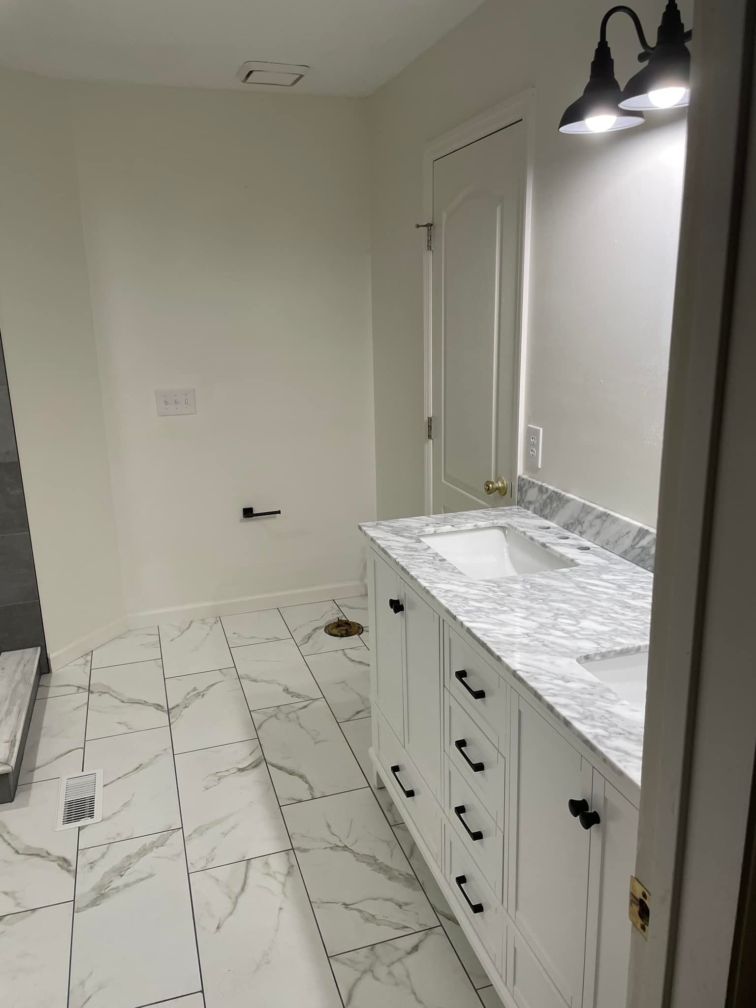 Bathroom vanity and mirror with double lights, white cabinetry, and patterned tile floor.