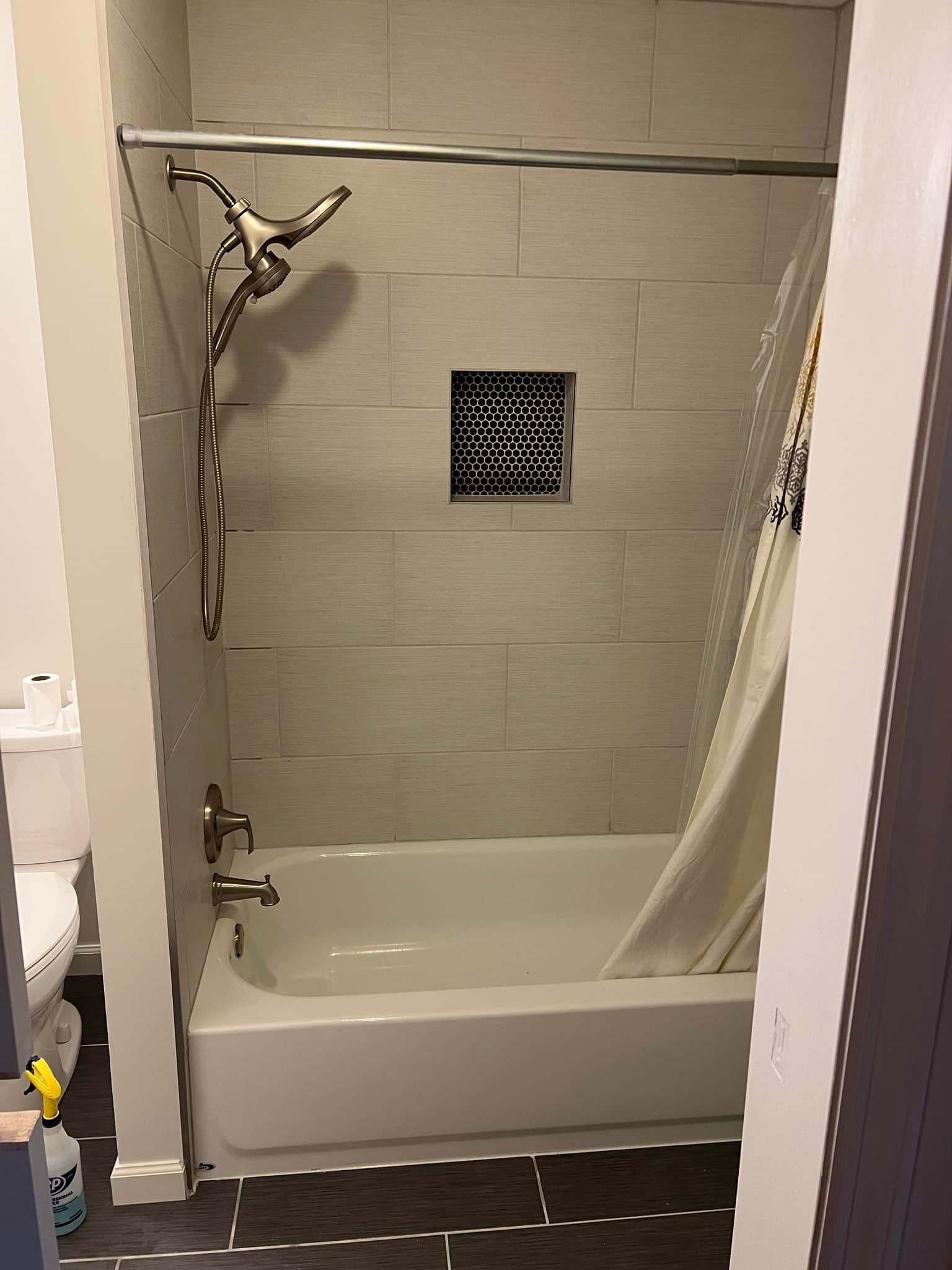 Bathroom shower with tub, beige tile, shower curtain, and wall-mounted showerhead.