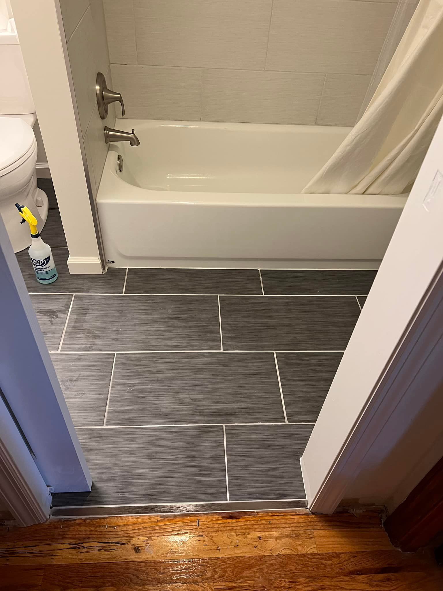 Bathroom doorway with dark tile floor and a white bathtub in the background.