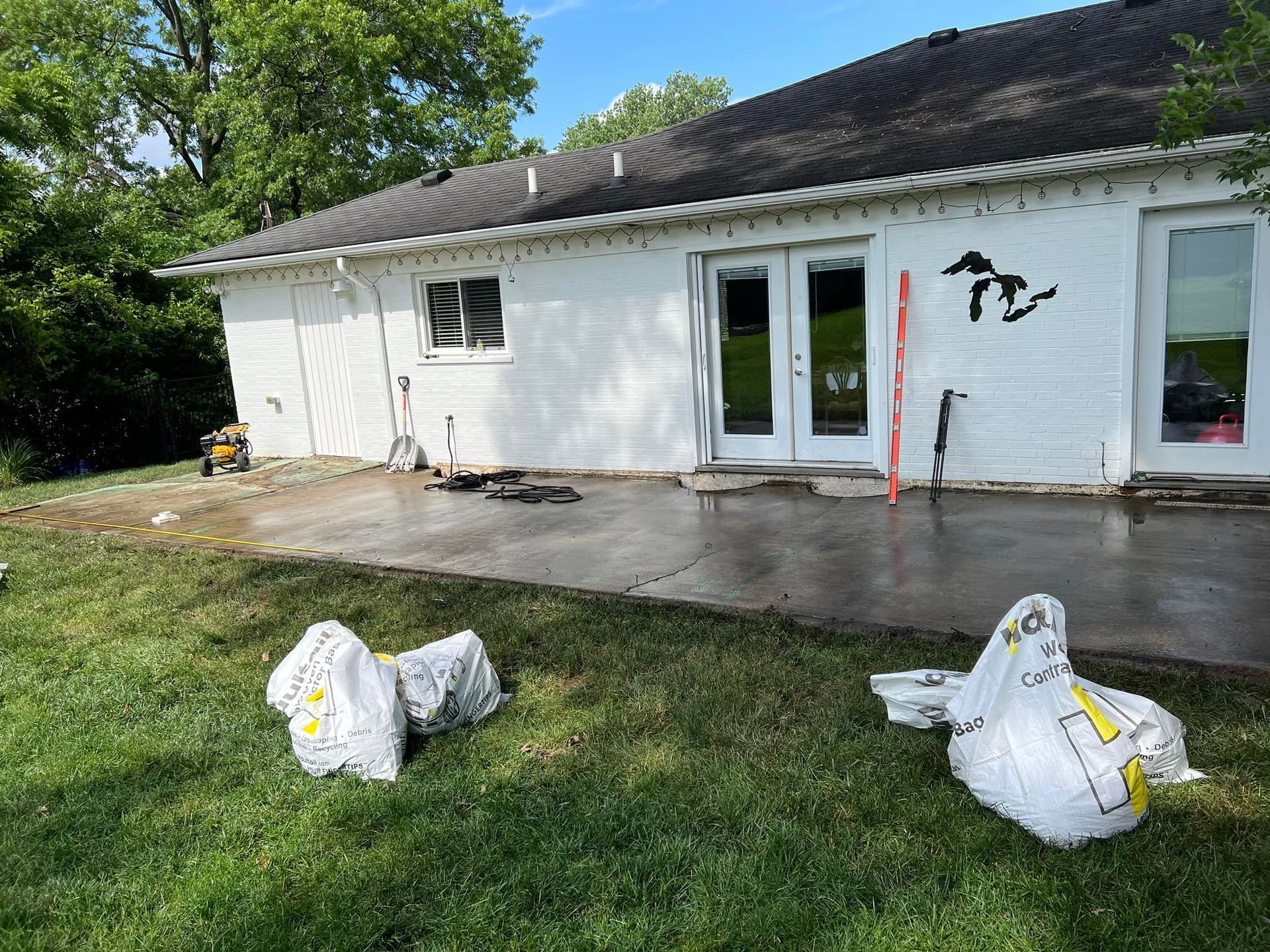 White house exterior with a concrete patio, lawn, and two white bags in the foreground