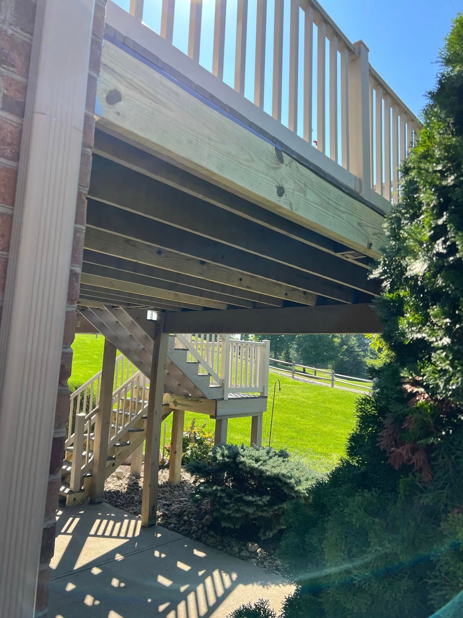 Backyard deck on stilts with stairs and railing, shaded underneath, beside a grassy yard