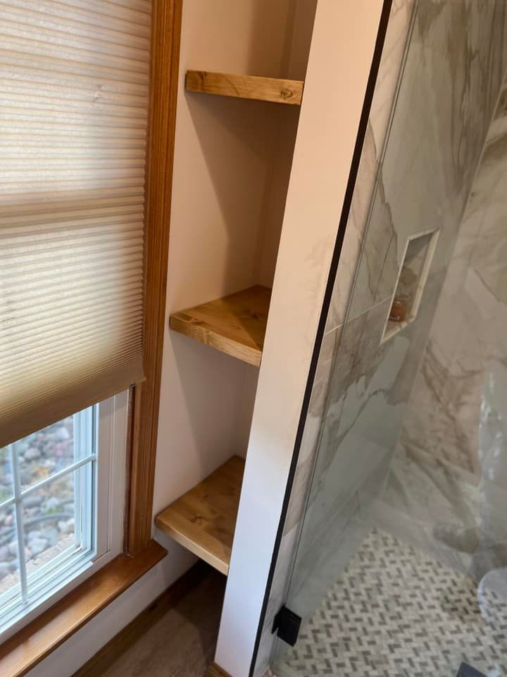 Narrow bathroom corner shelves beside a window and tiled shower wall