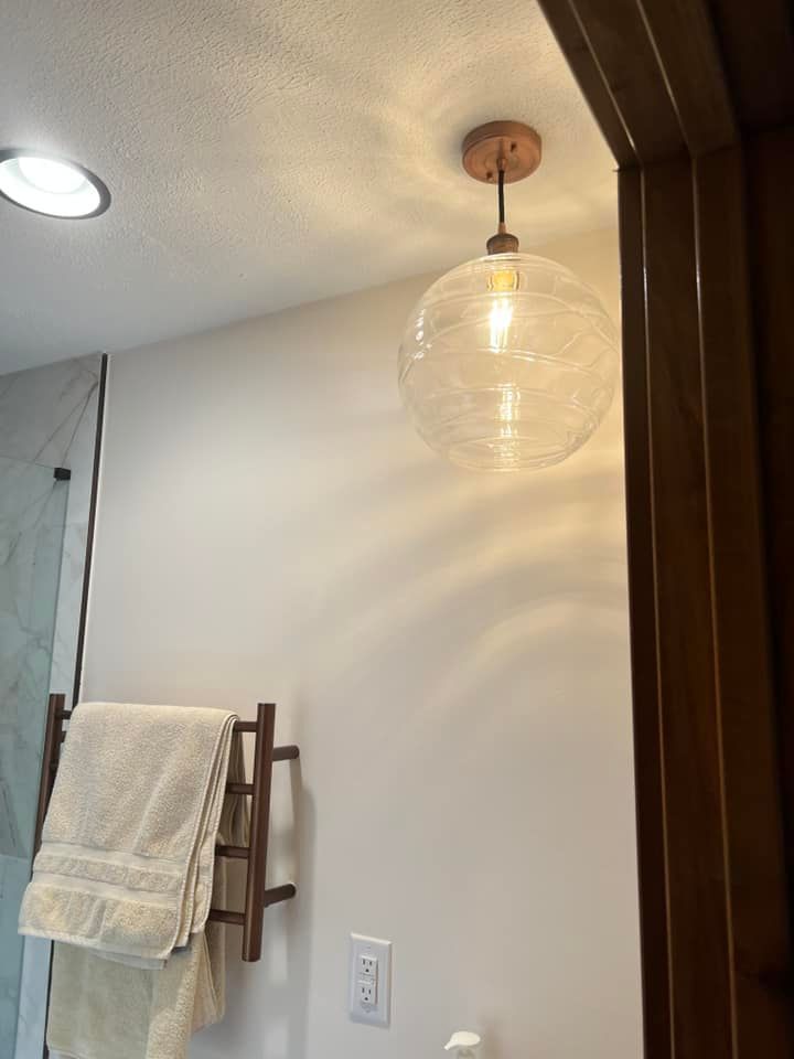 Bathroom corner with towel rack, hanging glass pendant light, and mirror edge.