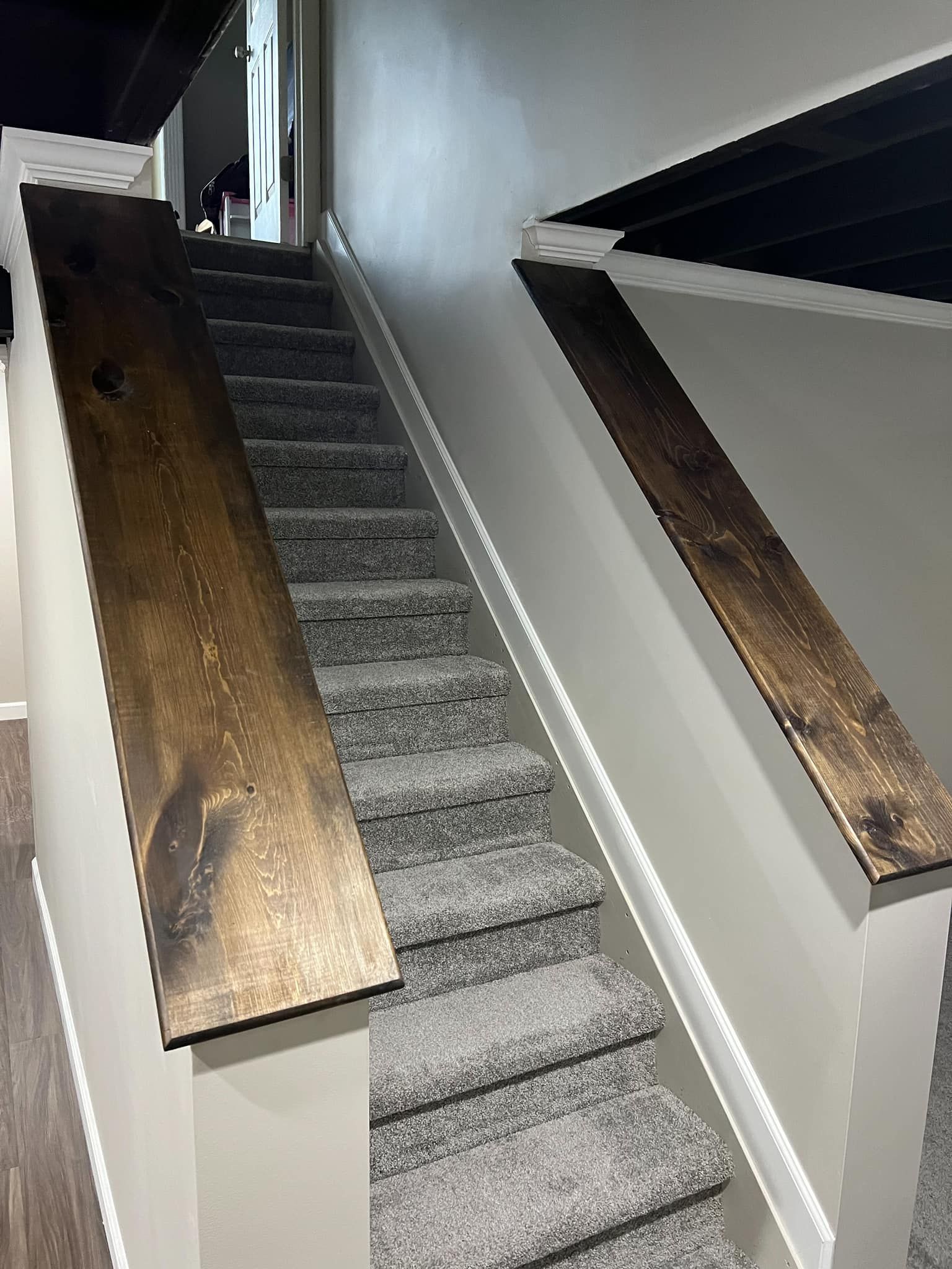 Narrow carpeted staircase with bronze handrails and white walls in a dim interior hallway